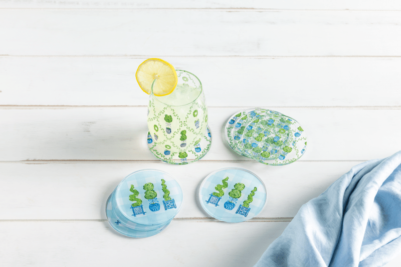 CHINOISERIE THREE TOPIARY COASTER AND OTHER TOPIARY COASTERS ON WOOD TABLE WITH DRINK AND LEMON
