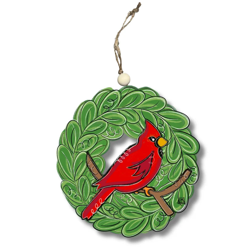 A decorative hanging ornament shaped like a green leafy wreath with a red cardinal perched in the center, suspended by a twine string and white bead on a white background.