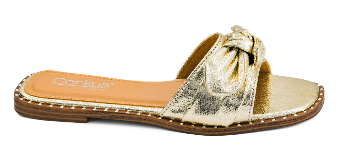 Metallic gold crinkle slide sandals with oversized knotted bow detail and flat slip-on design | Walker Boutique