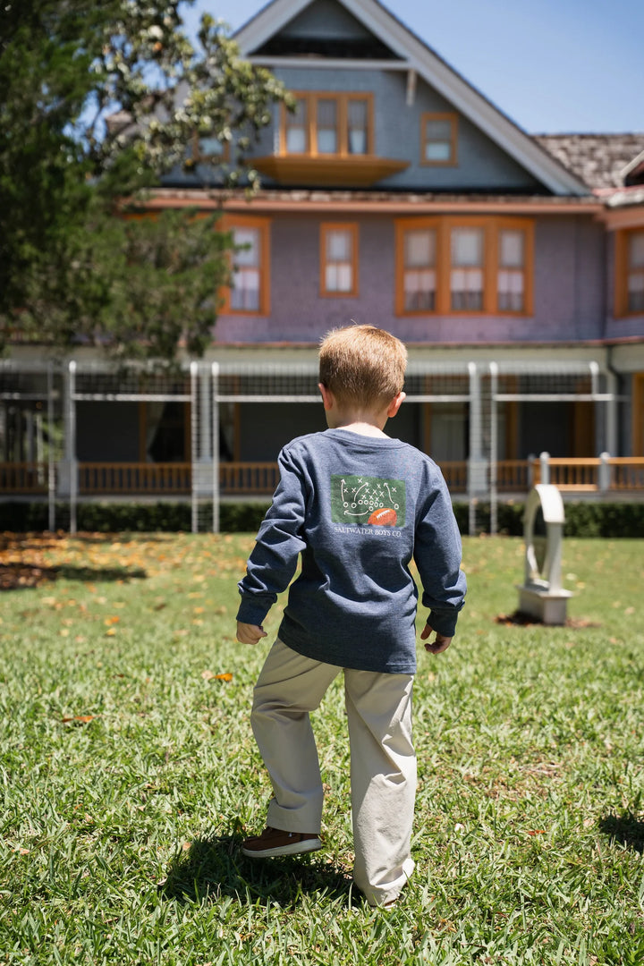 LITTLE BOY WEARING HEATHER BLUE PLAYBOOK LONG SLEEVE GRAPHIC TEE IN GRASSY YARD