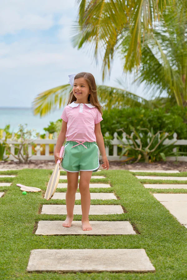 Young girl standing on a stepping stone path by the beach with palm trees in the background
