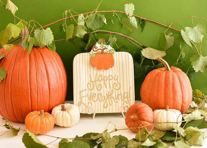 Decorative setup with pumpkins and a sign on a green background