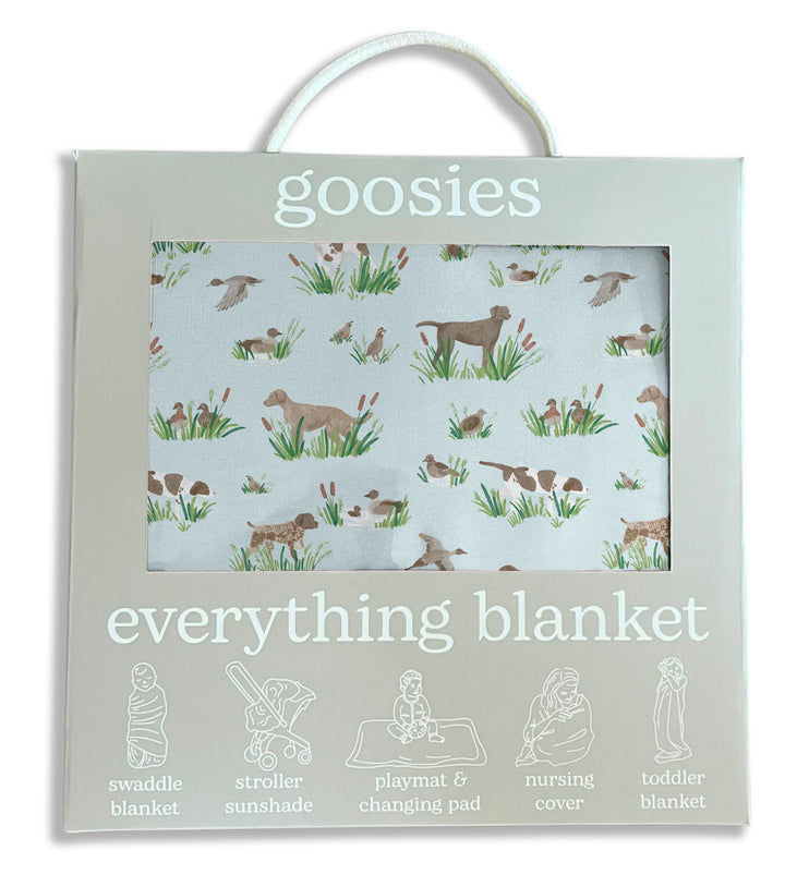 Goosies Everything Blanket in its packaging, featuring a light sage green box with a clear window showing a white blanket printed with a brown and green dog and duck hunting pattern.
