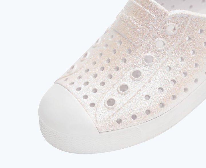 Close-up of a white sneaker with holes on a light gray background
