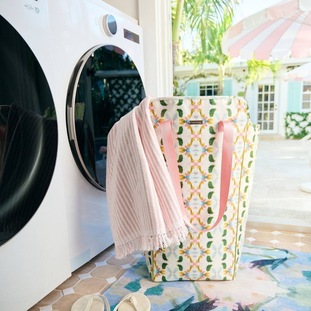 Patterned laundry basket with pink towel next to a washing machine outdoors