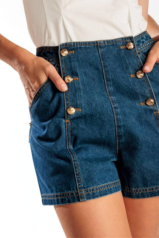 Blue denim shorts with gold buttons worn by a person on a white background