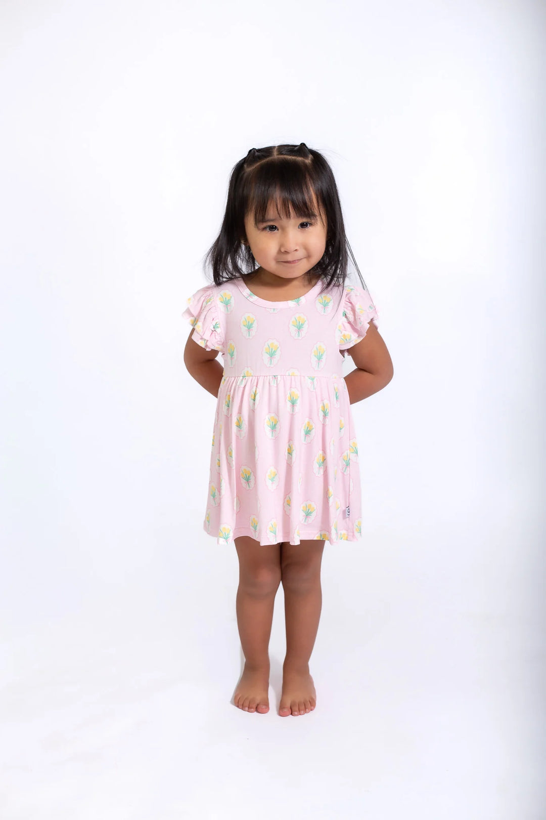 Young girl wearing a pink dress with a white background