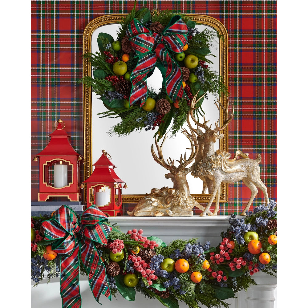 Decorative Christmas mantel with wreath, garland, and figurines against a plaid background