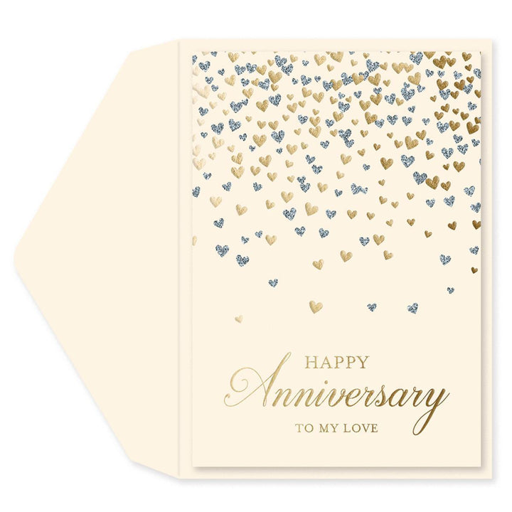 A cream-colored anniversary greeting card with a matching envelope. The card features a pattern of falling gold and blue glitter hearts, with 'HAPPY Anniversary TO MY LOVE' printed in elegant gold lettering at the bottom.