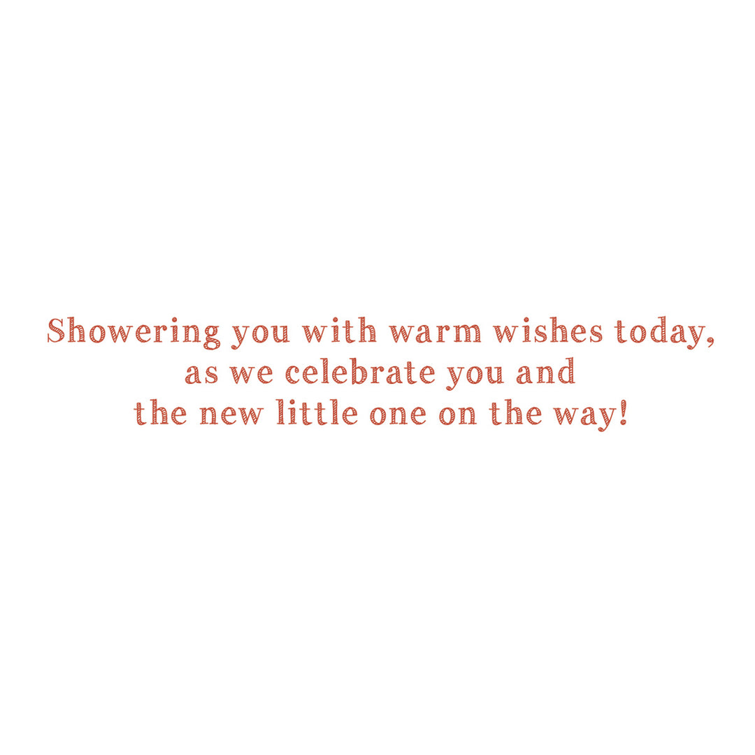 A square white card or print featuring centered coral-red text that reads, 'Showering you with warm wishes today, as we celebrate you and the new little one on the way!'.