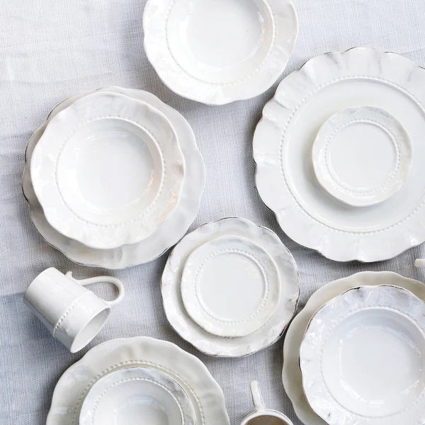Set of white ceramic plates and cups on a light gray background