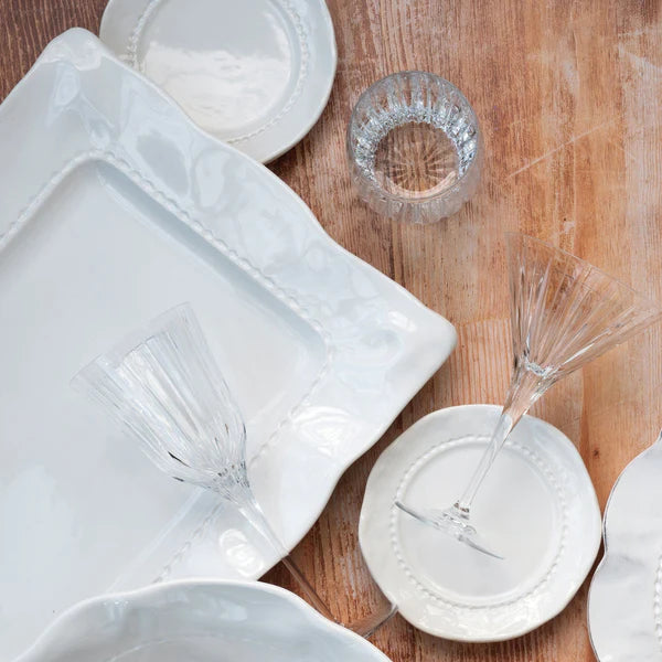 White ceramic tableware including plates, bowls, and glasses on a wooden surface.