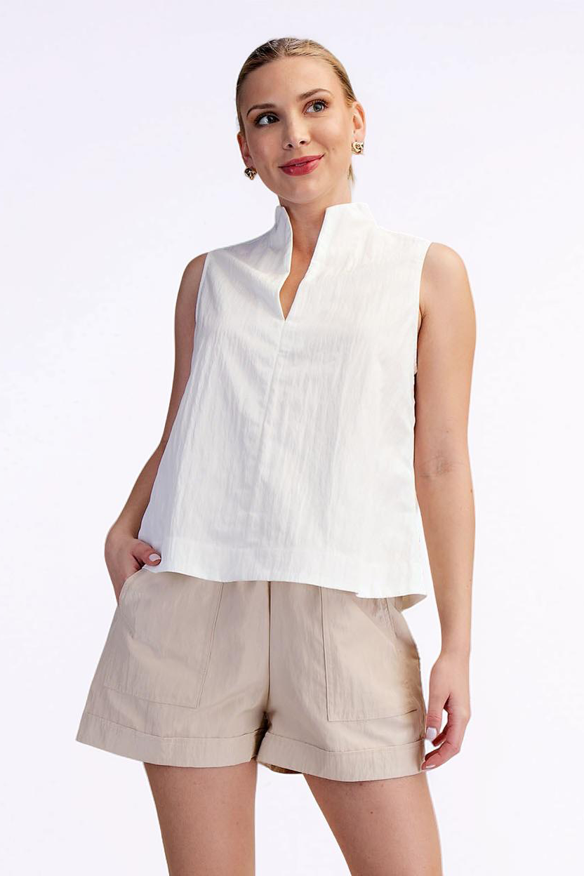 Woman wearing a white sleeveless top and beige shorts on a white background