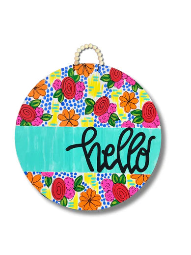 Round wooden door hanger with colorful floral pattern, teal stripe across center, and “hello” in black script, featuring a beaded loop for hanging.