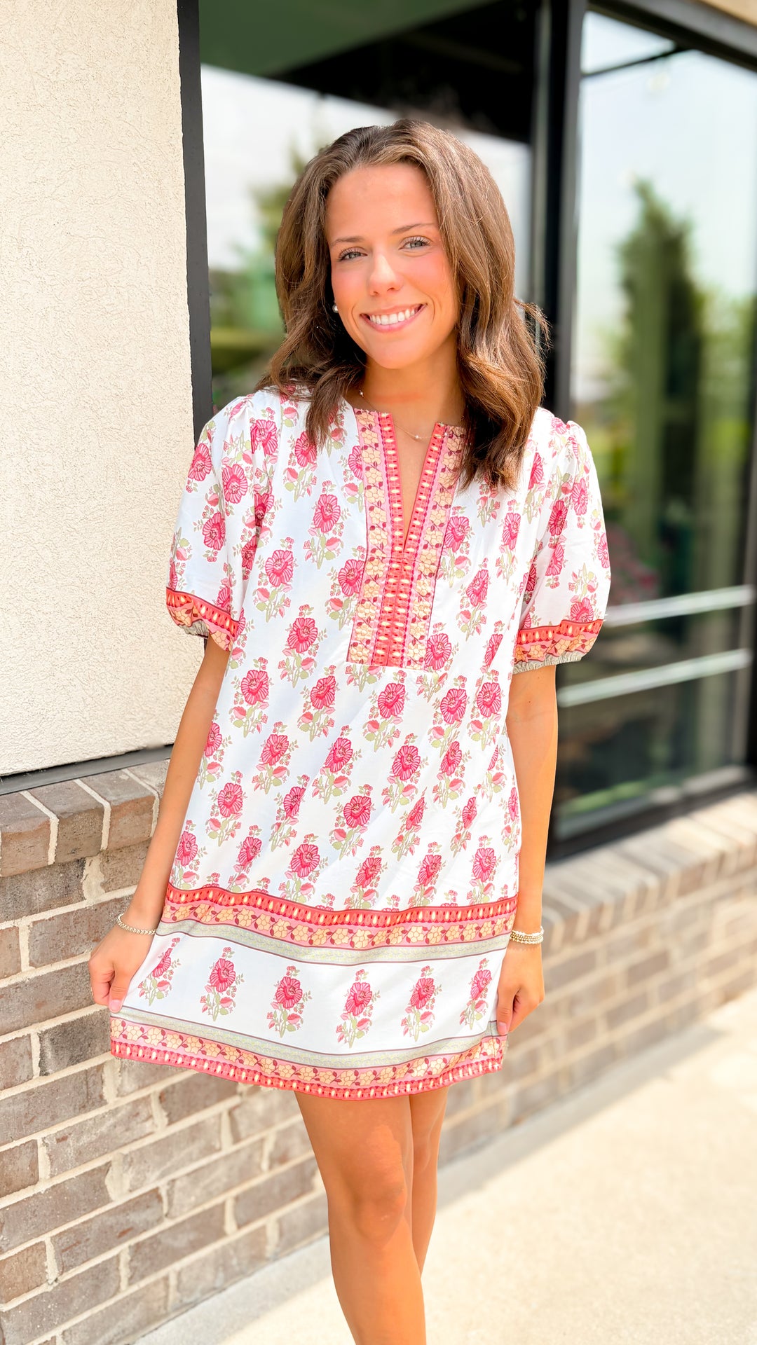 Woman wearing a floral dress standing outside a building.