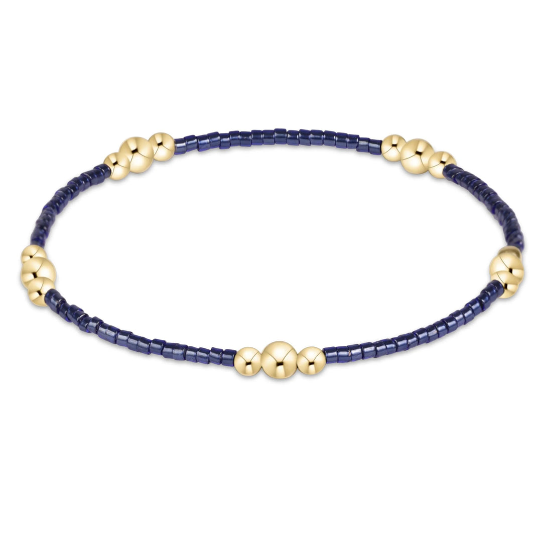NAVY BEADED BRACELET WITH 3 GOLD BEADED CLUSTERS ON WHITE BACKGROUND