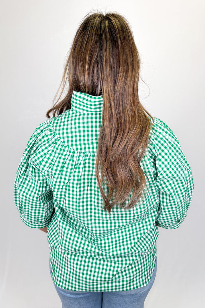Person wearing a green and white checkered jacket on a plain background
