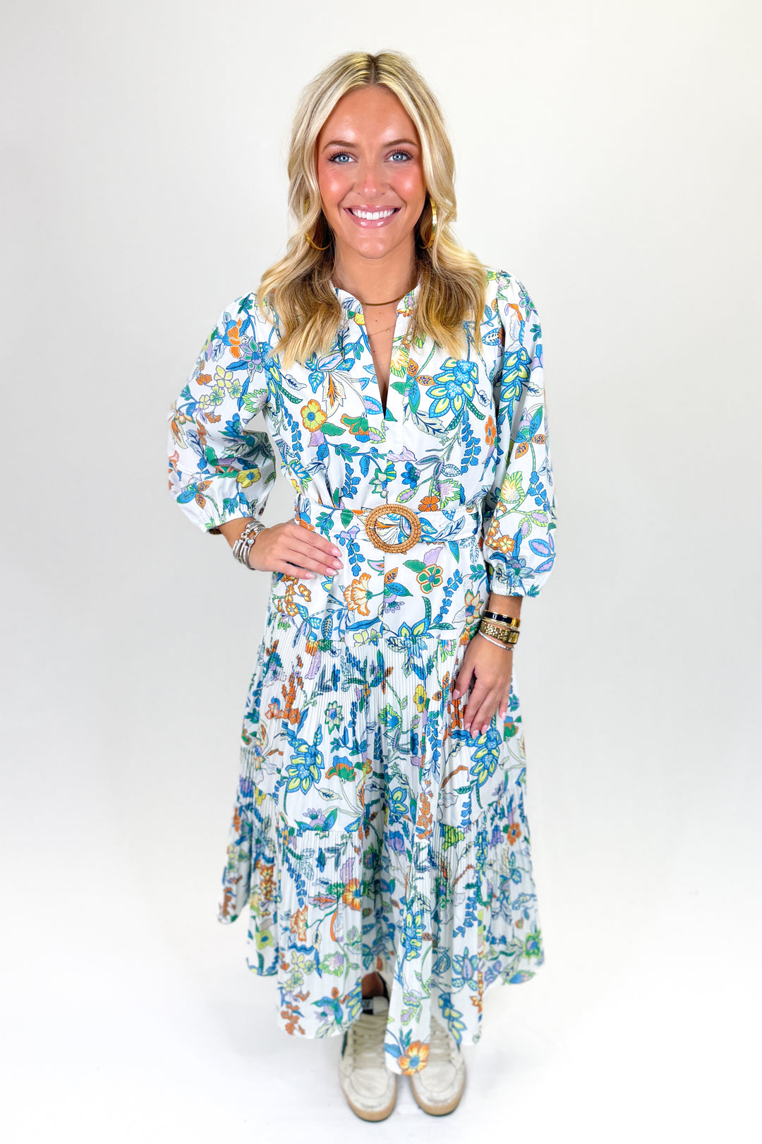 Woman wearing a multi colored, belted, floral midi dress.