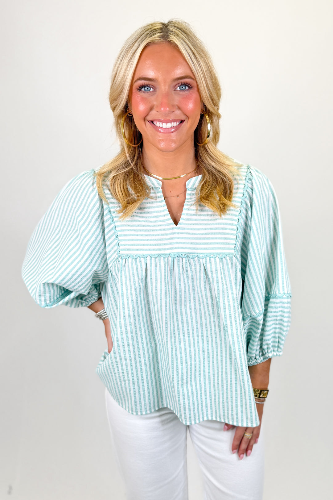 Woman wearing a striped vneck top paired with white pants.