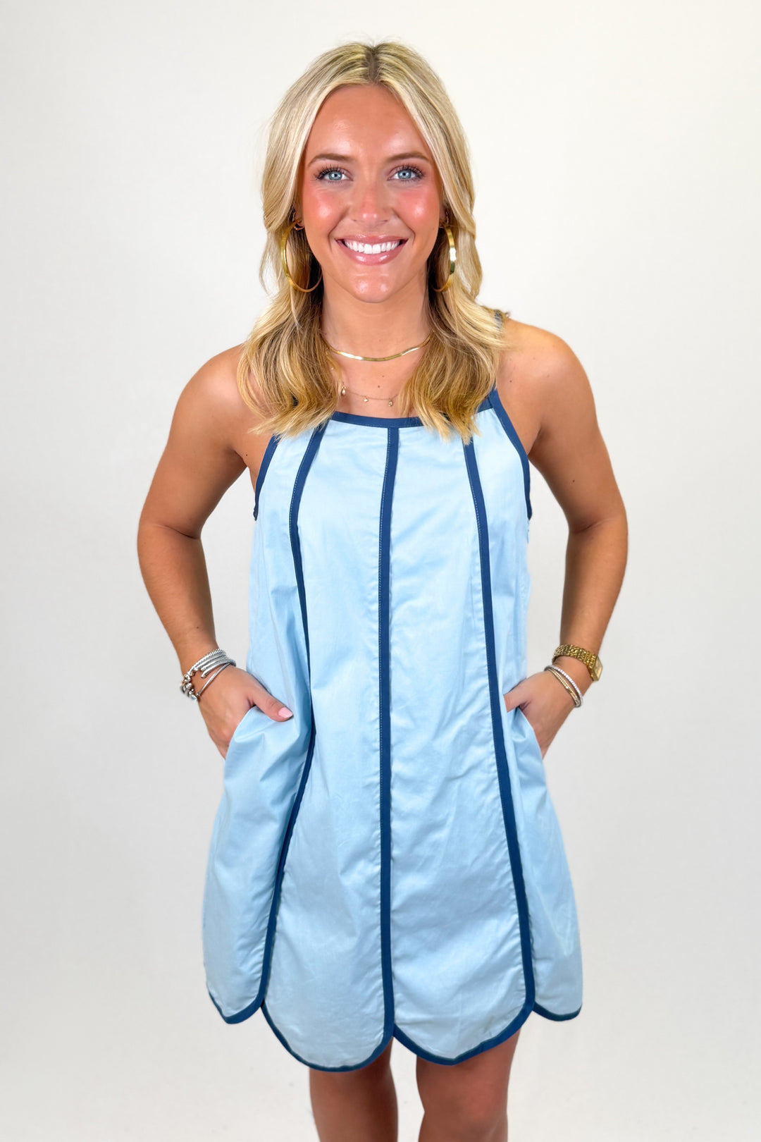 Woman wearing a baby blue short dress with navy trim.