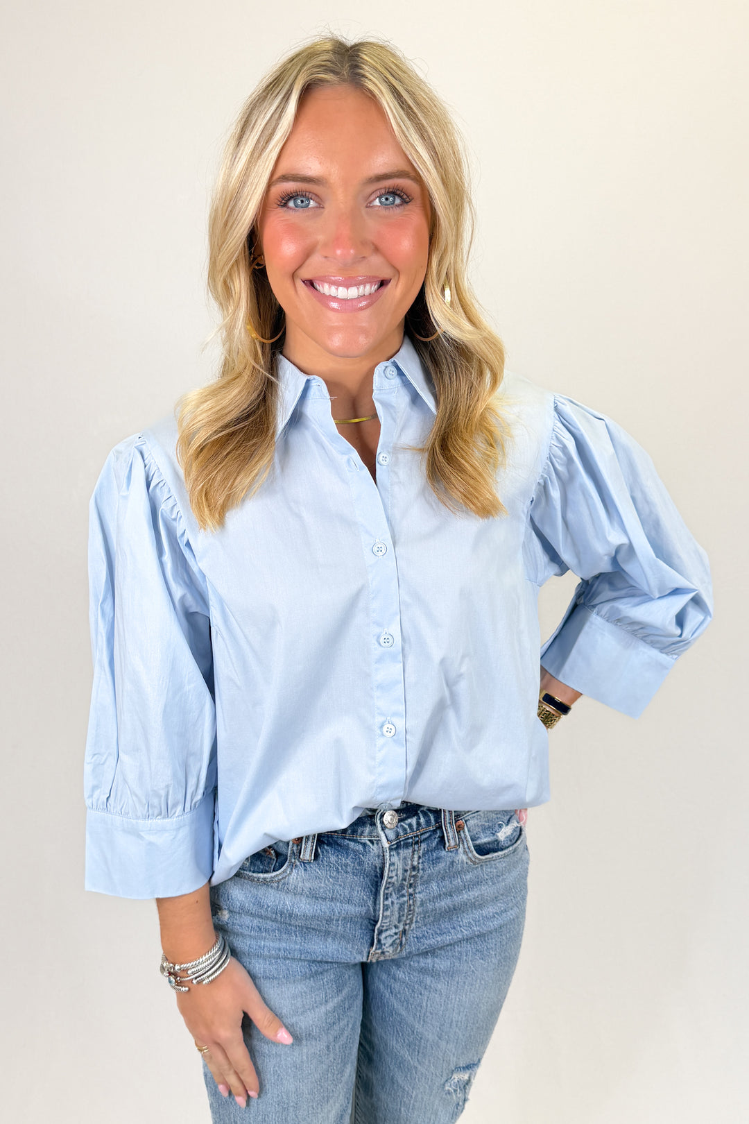 Light blue button-front blouse with puff sleeves, classic collar, and relaxed fit paired with denim