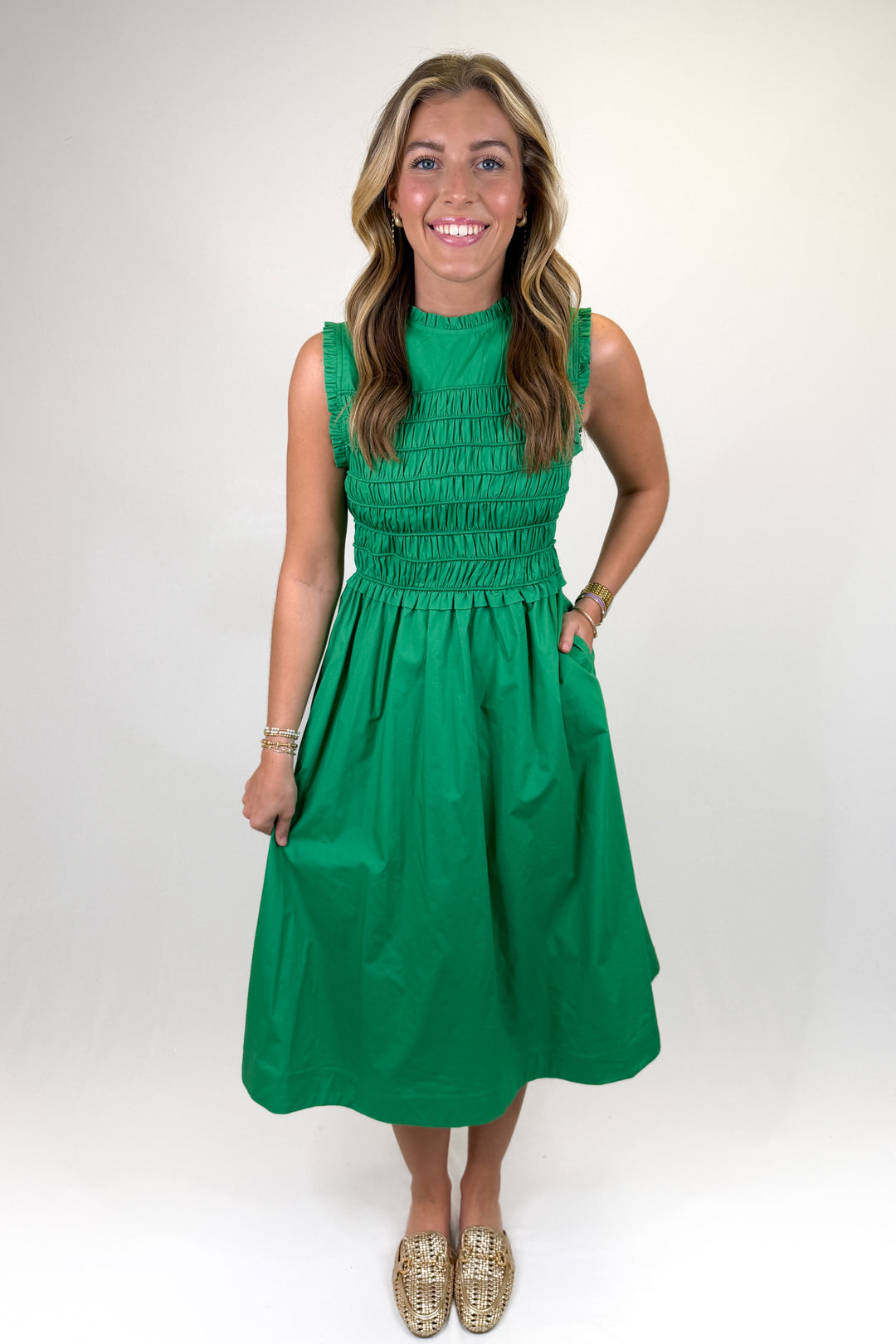 Green sleeveless midi dress with smocked bodice, ruffle shoulder detail, and high neckline