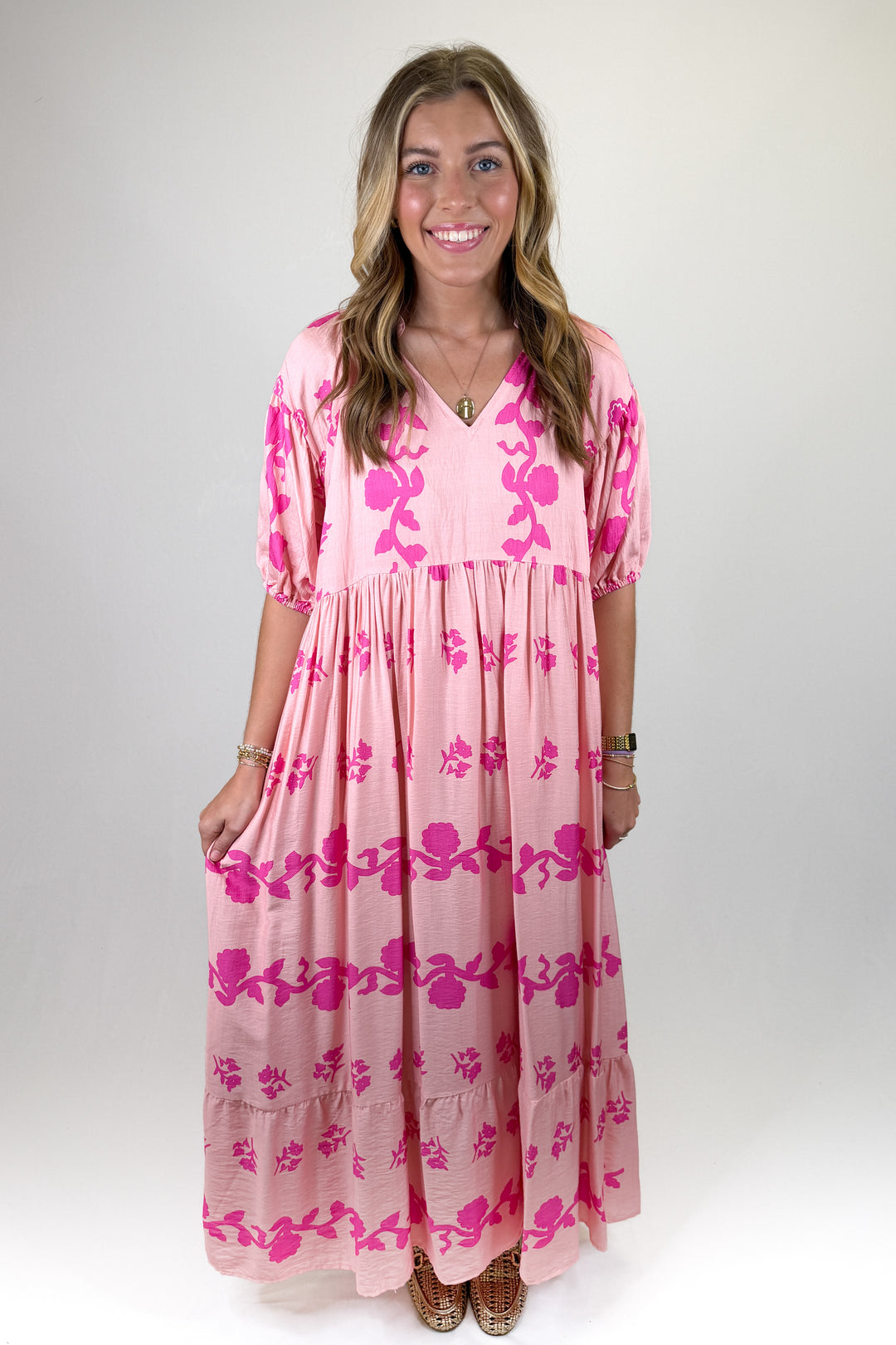 Pink maxi dress with bold fuchsia floral print, flowy tiered skirt and puff sleeves, feminine statement dress perfect for spring and summer