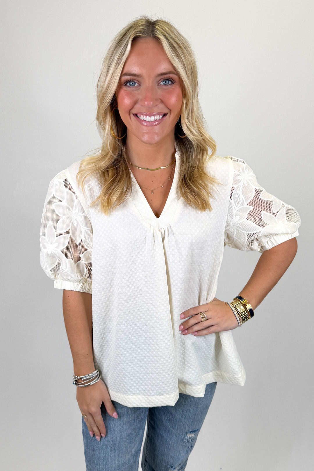 Cream textured blouse with sheer floral lace puff sleeves and V-neckline, feminine lightweight top perfect for spring styling with denim