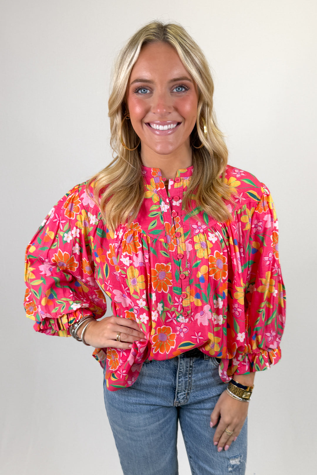 Bright pink floral blouse with colorful orange, green, and yellow flowers, puff sleeves and button front, vibrant spring statement top styled with denim