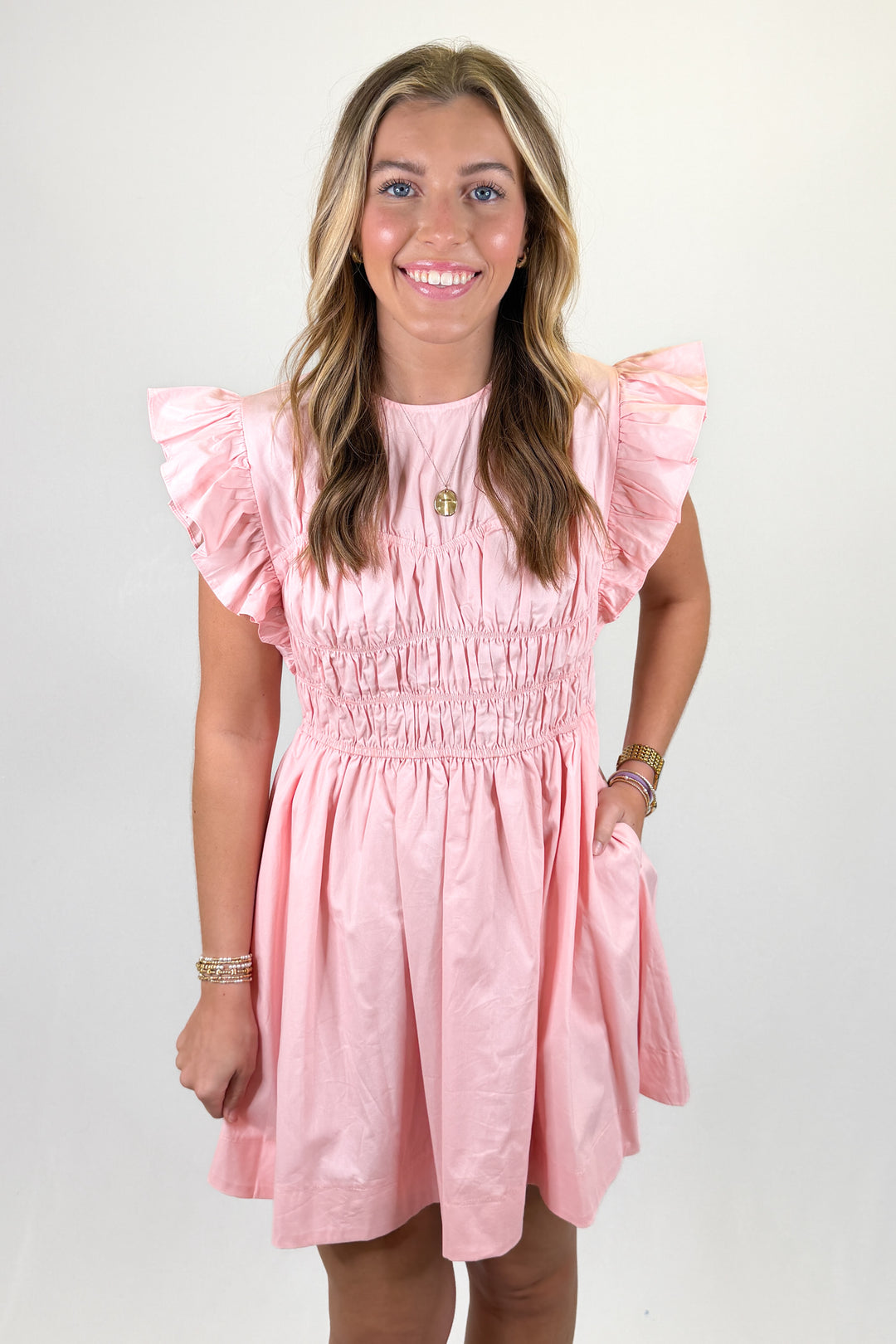 Pink ruffle sleeve mini dress with smocked bodice, round neckline, and flowy skirt