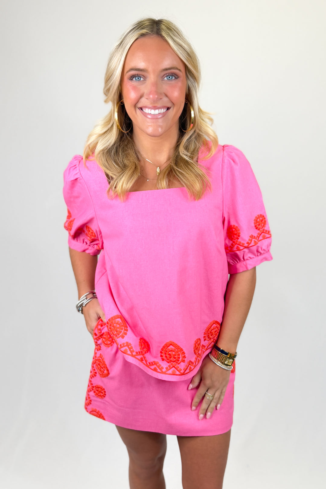 Bright pink women’s set with square neckline, puff sleeves, and red embroidered scalloped hem