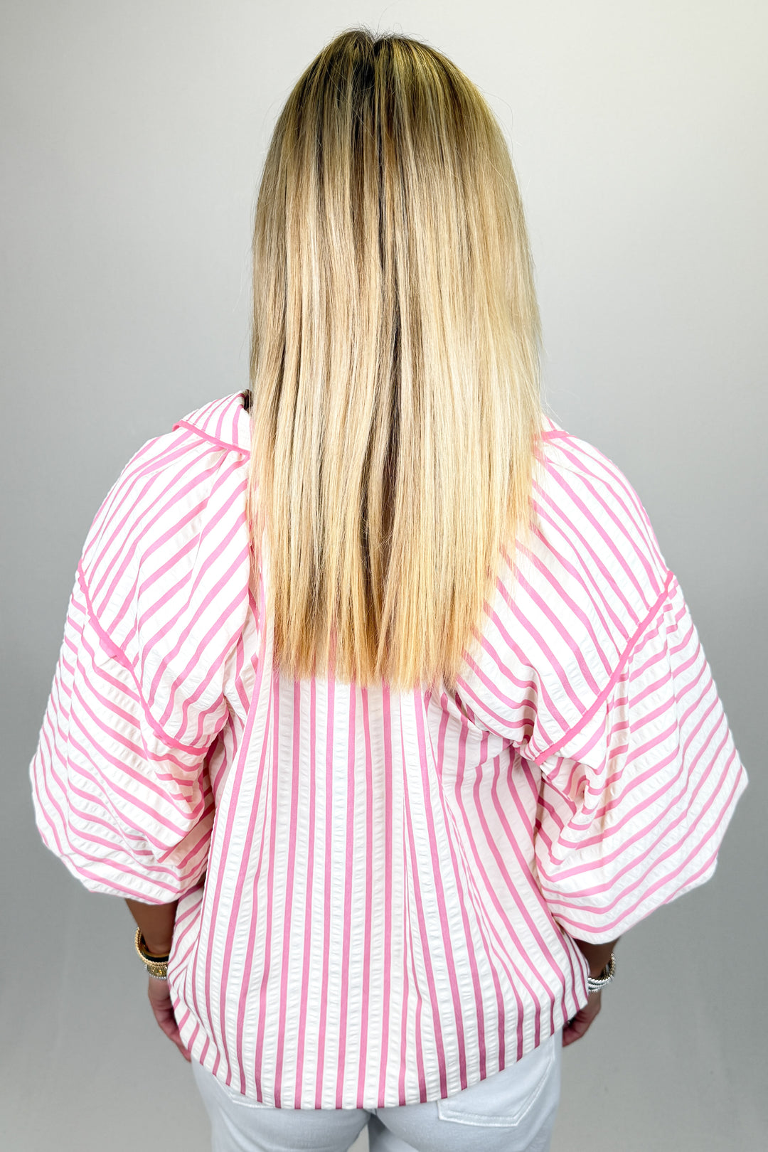 Boutique women’s pink and white striped top with v-neckline, relaxed fit, and lightweight fabric