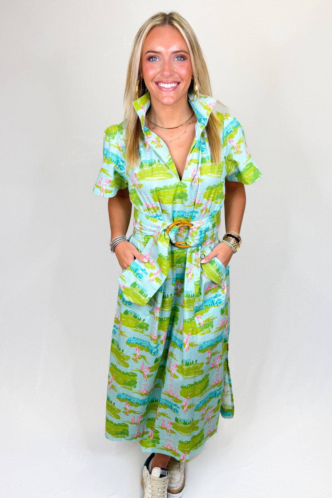 Women’s green and blue printed midi dress with collar neckline, short sleeves, and bamboo buckle belt, styled with sneakers.
