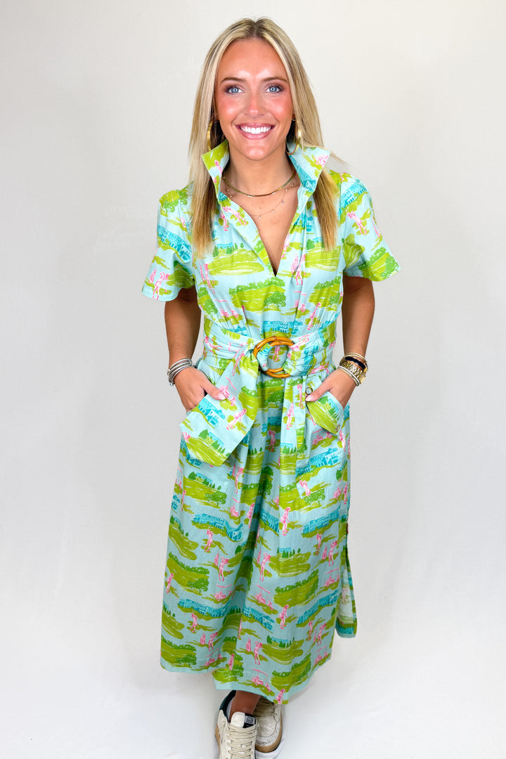 Women’s green and blue printed midi dress with collar neckline, short sleeves, and bamboo buckle belt, styled with sneakers.