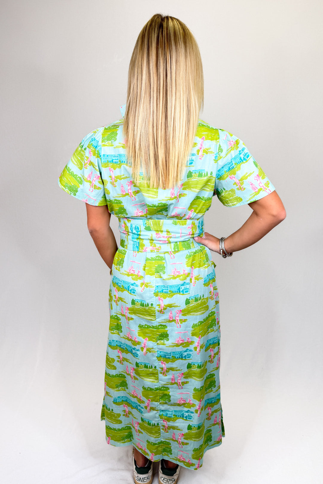 Women’s green and blue printed midi dress with collar neckline, short sleeves, and bamboo buckle belt, styled with sneakers