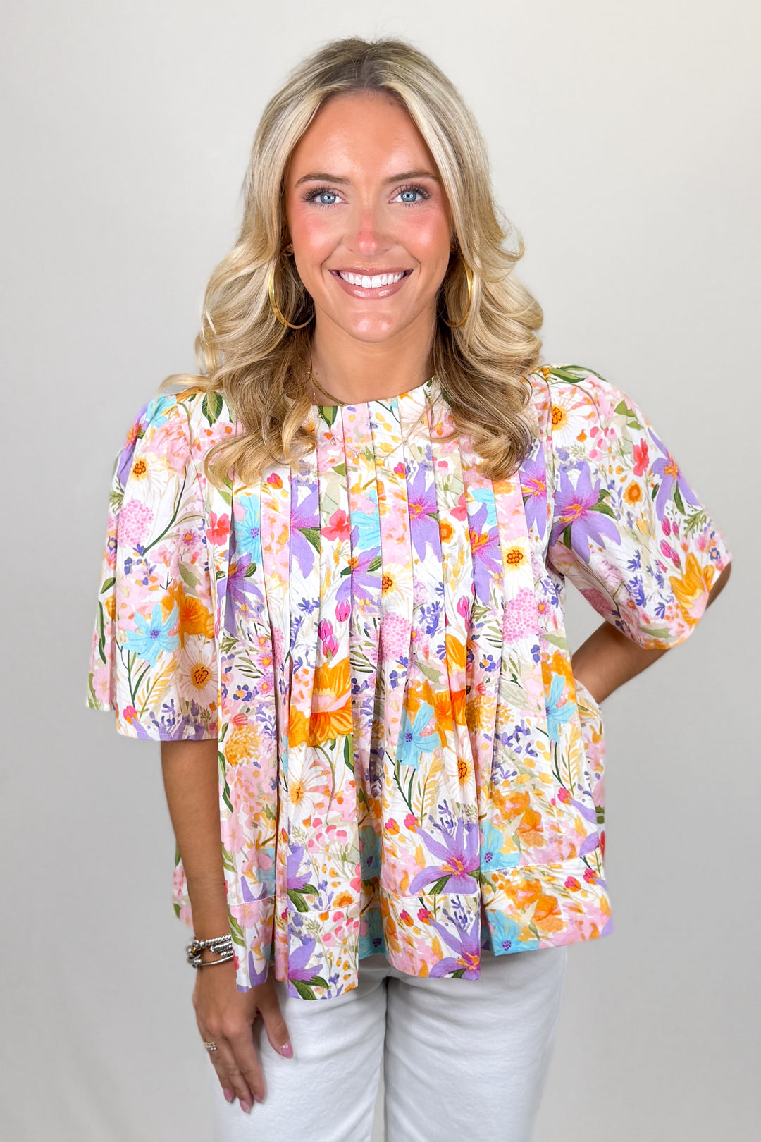 Multicolor floral blouse for women with short sleeves and flowy pleated silhouette styled with white pants