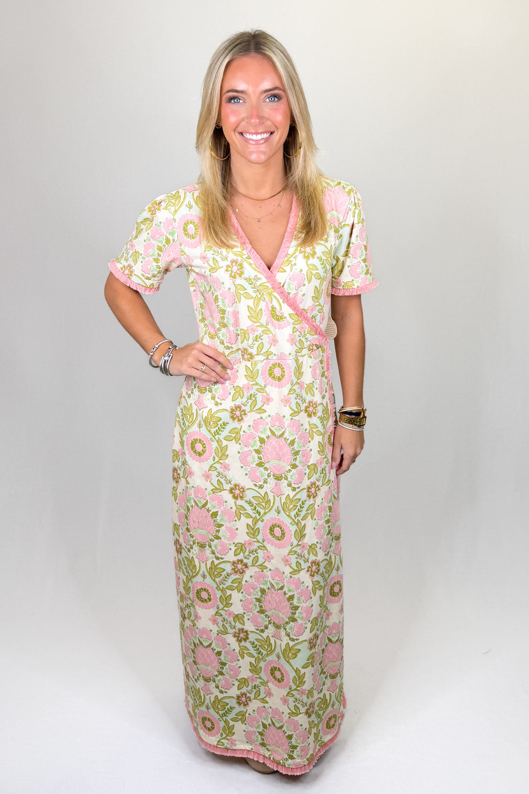 Pink and green floral print maxi dress with short sleeves, wrap-style bodice, V-neckline, and contrast trim, featuring a flattering fit and lightweight feel