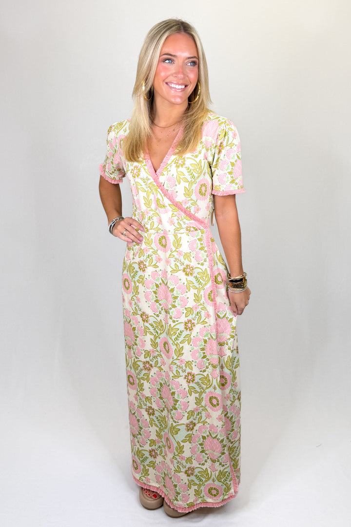 Pink and green floral print maxi dress with short sleeves, wrap-style bodice, V-neckline, and contrast trim, featuring a flattering fit and lightweight feel
