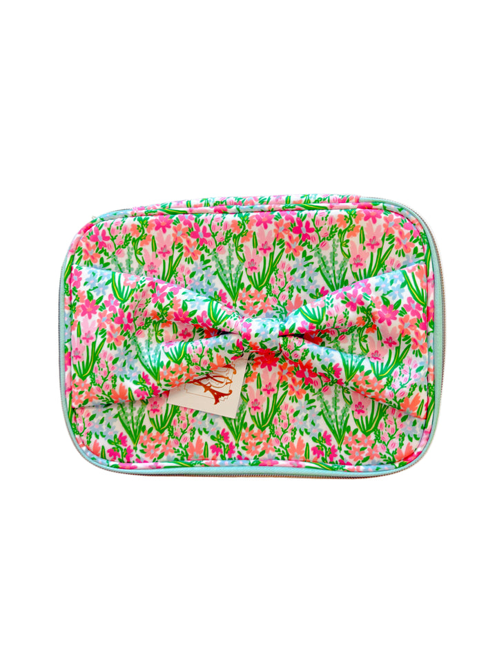 Front view of floral cosmetic bag featuring pink and green flower print and oversized matching bow.