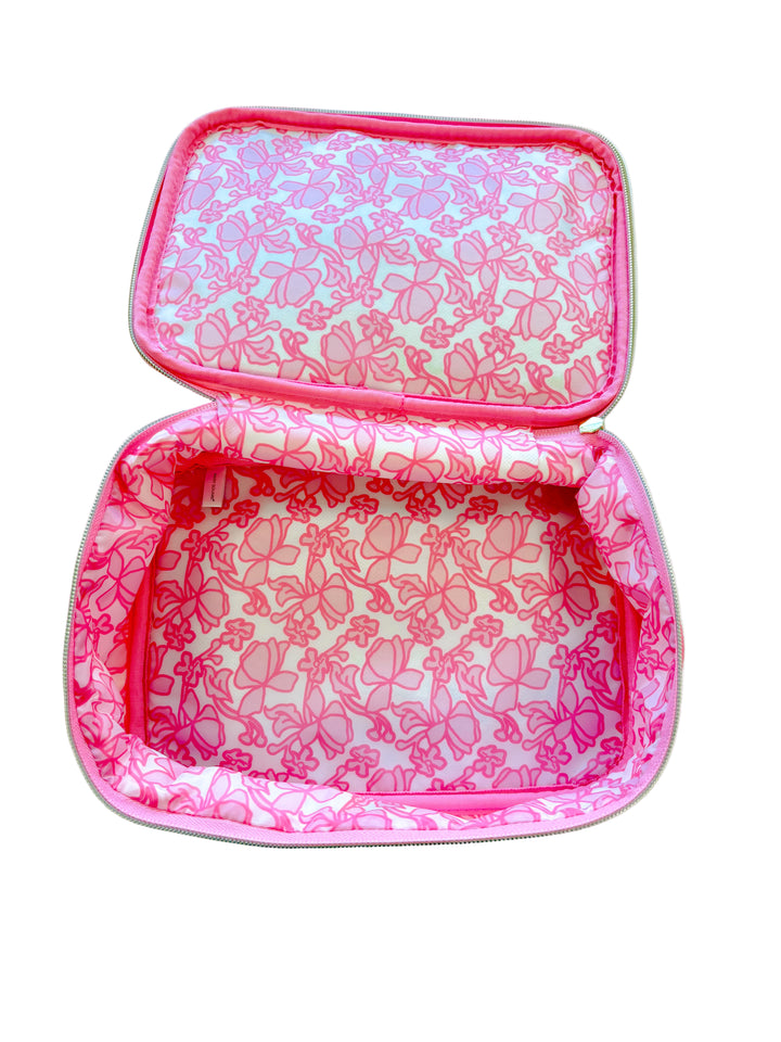 Interior view of hot pink cosmetic bag with all-over pink bow print lining.