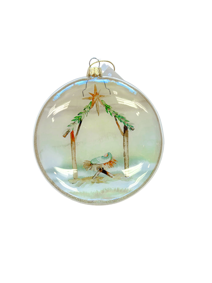 Round Christmas ornament with watercolor nativity scene featuring baby Jesus in a manger.
