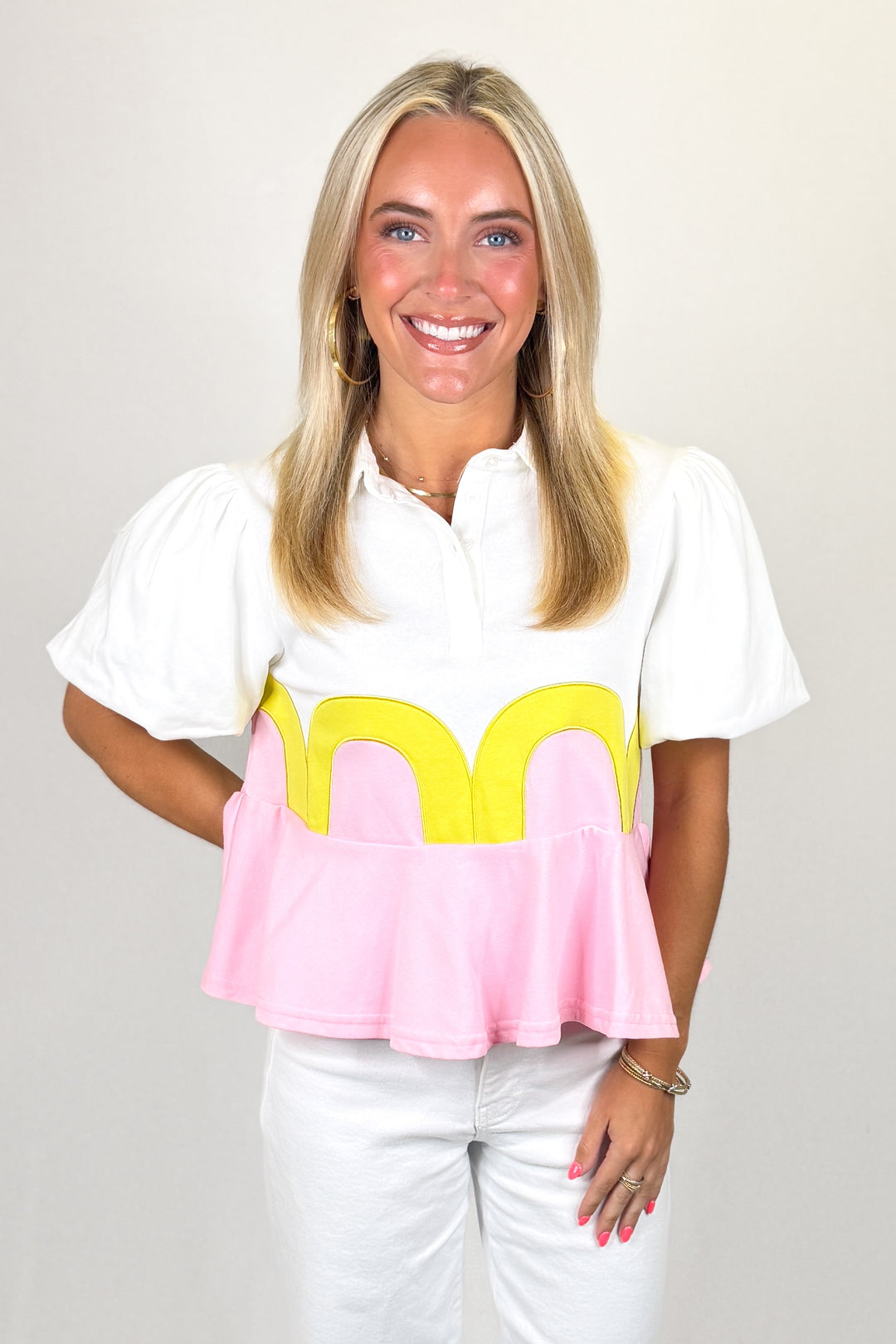 White top with puff sleeves and pink peplum hem with yellow scallop detail
