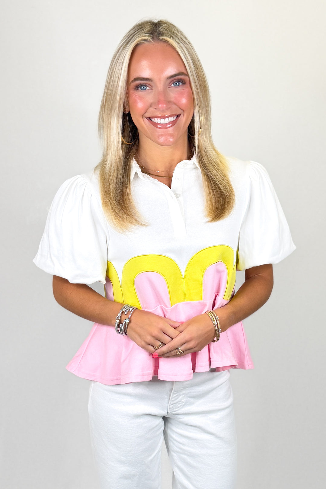 White top with puff sleeves and pink peplum hem with yellow scallop detail
