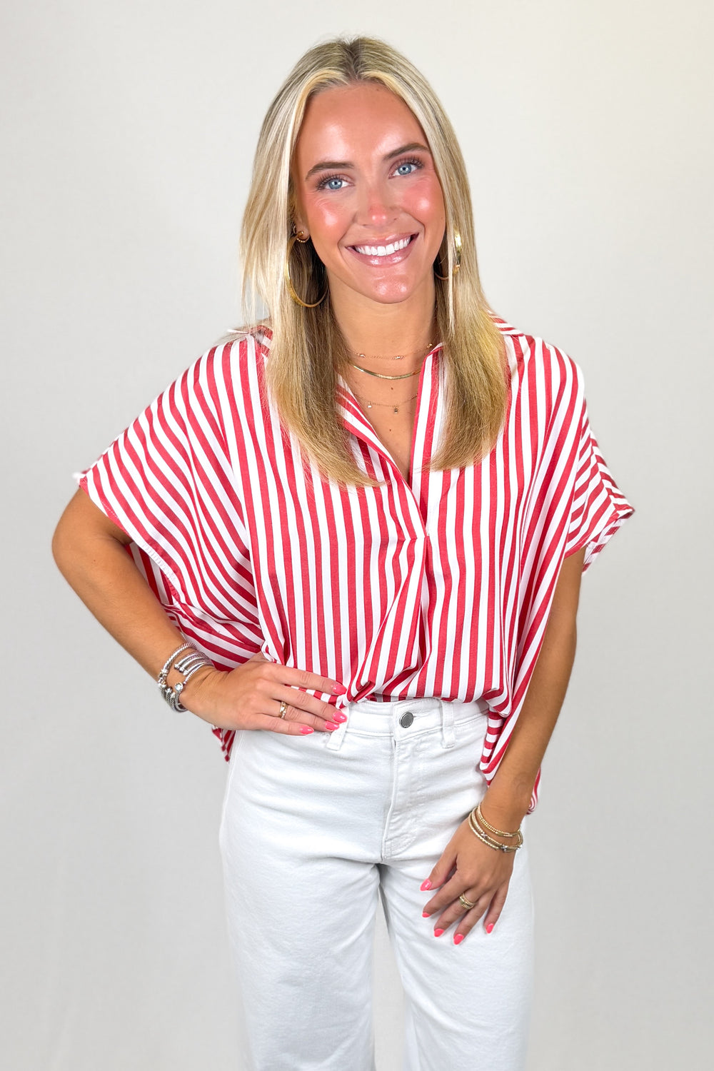 Red and white striped flutter sleeve blouse paired with white denim jeans and gold hoop earrings, styled for a bright summer boutique outfit.