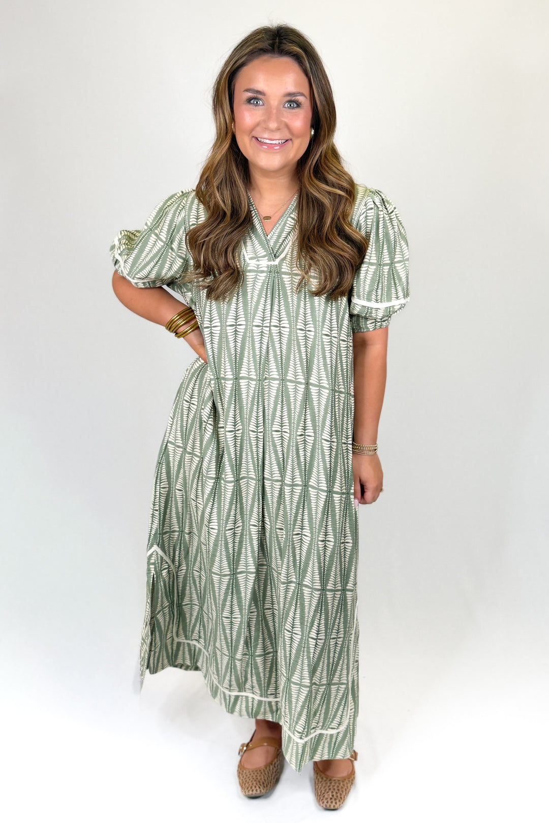 Woman wearing a green patterned dress on a white background