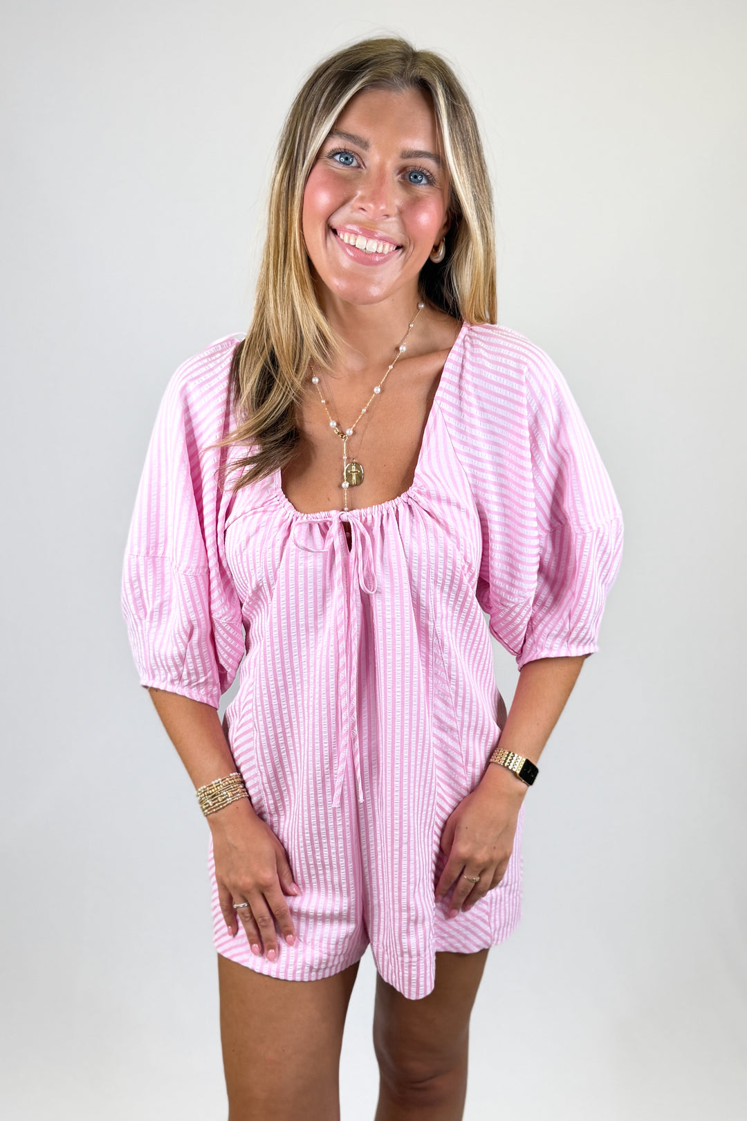 Woman wearing a pink striped outfit on a plain background