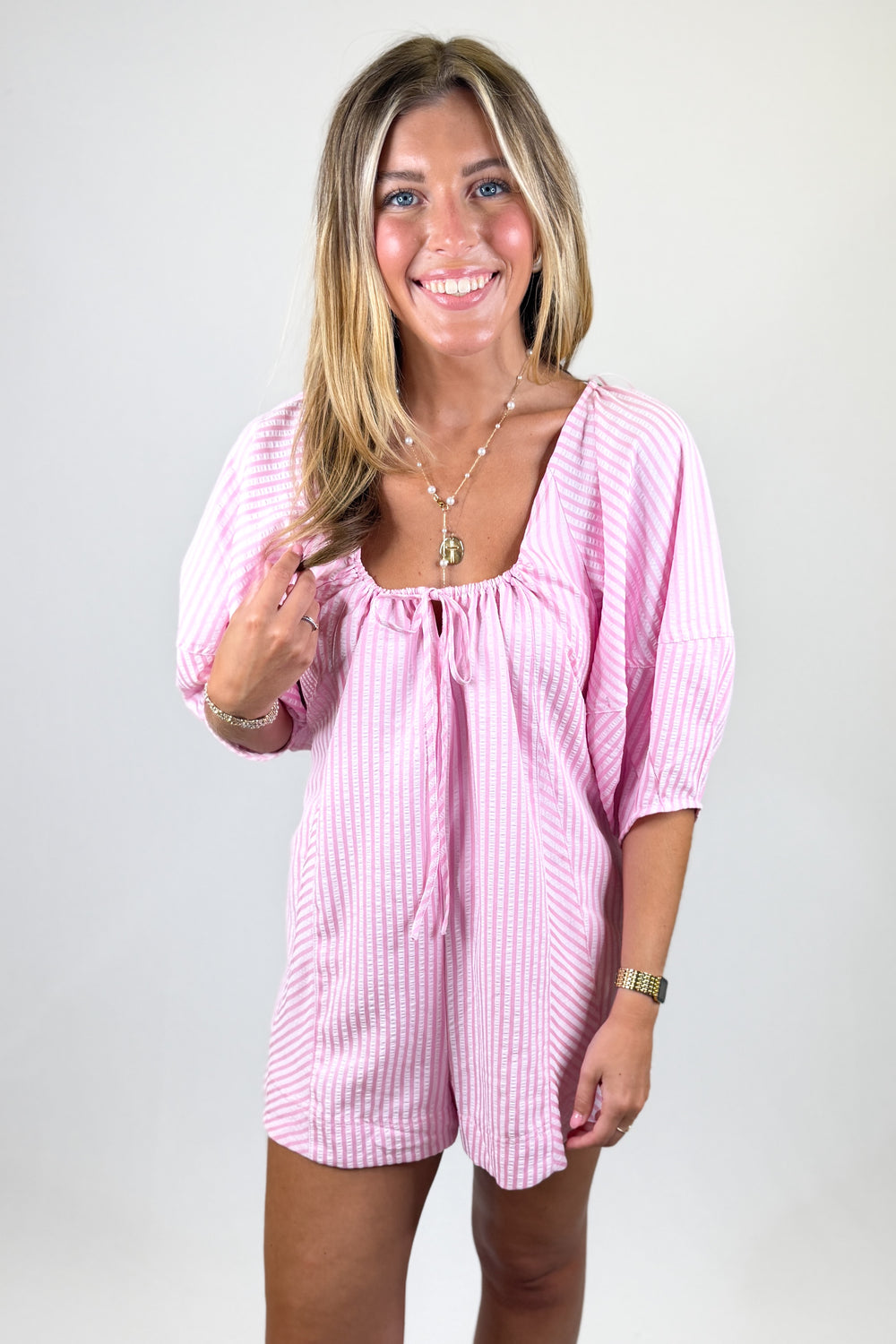 Woman wearing a pink striped dress against a plain background
