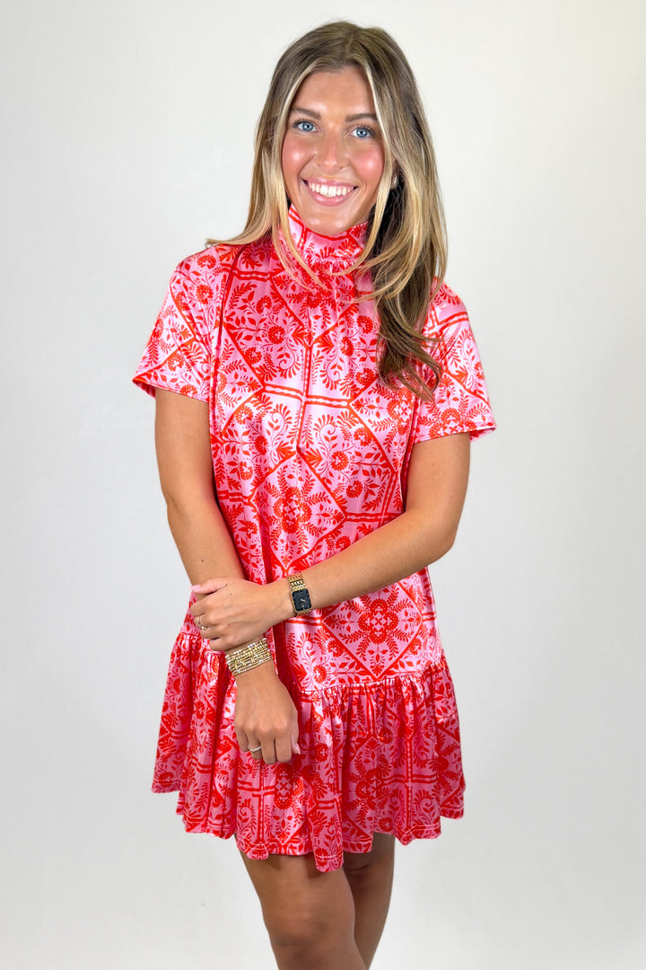 Woman wearing a red patterned dress against a white background