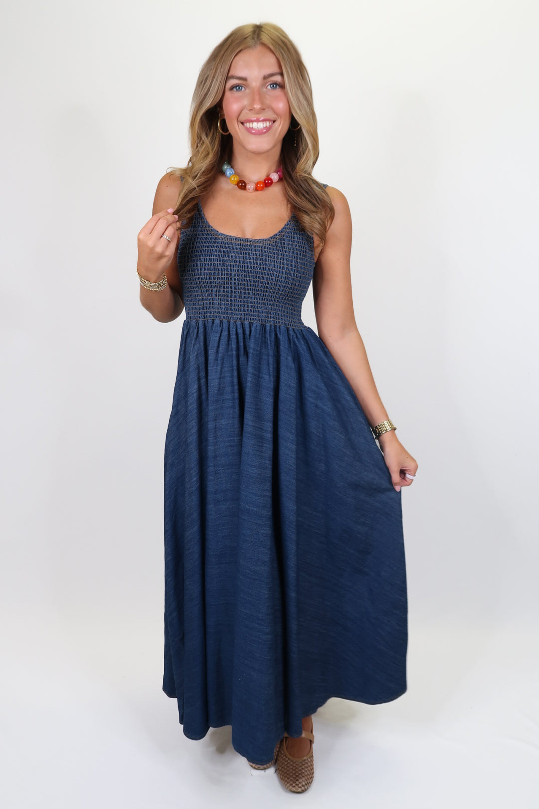 woman wearing denim smocked dress on plain background