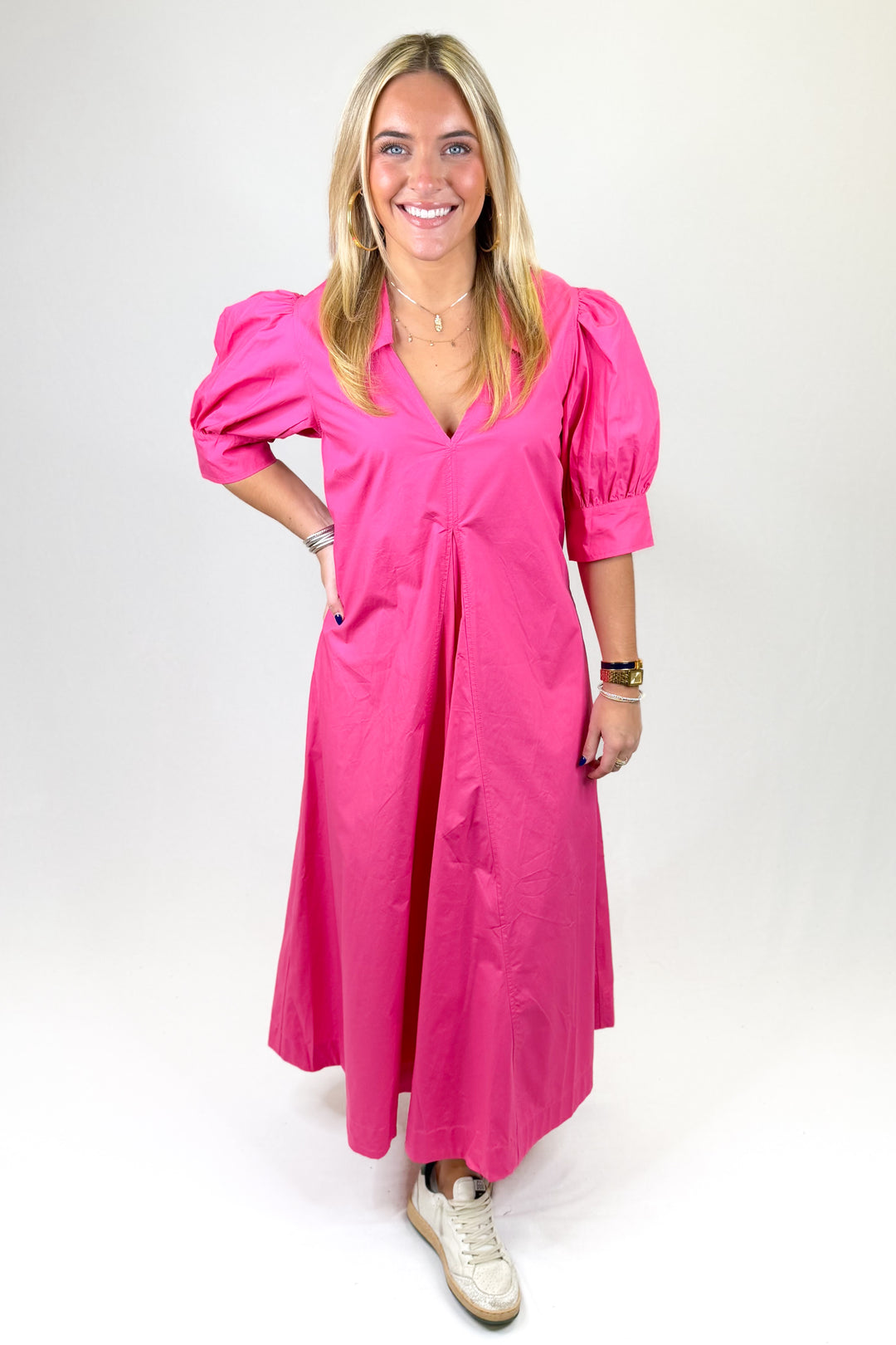 Woman wearing a bright pink dress with puff sleeves on a white background